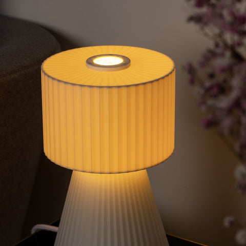 Lustra Plissé Glacier White lamp glowing with soft warm light in a styled room