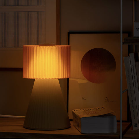 Lustra Plissé Apricot Beige lamp glowing warmly in a dark interior